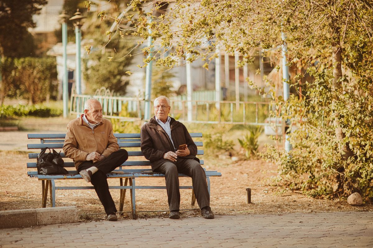 Two Medicare beneficiaries sitting on bench talking about buying a Medicare Advantage plan